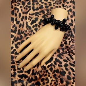 Creative black bracelet of beads, chains and ribbons.